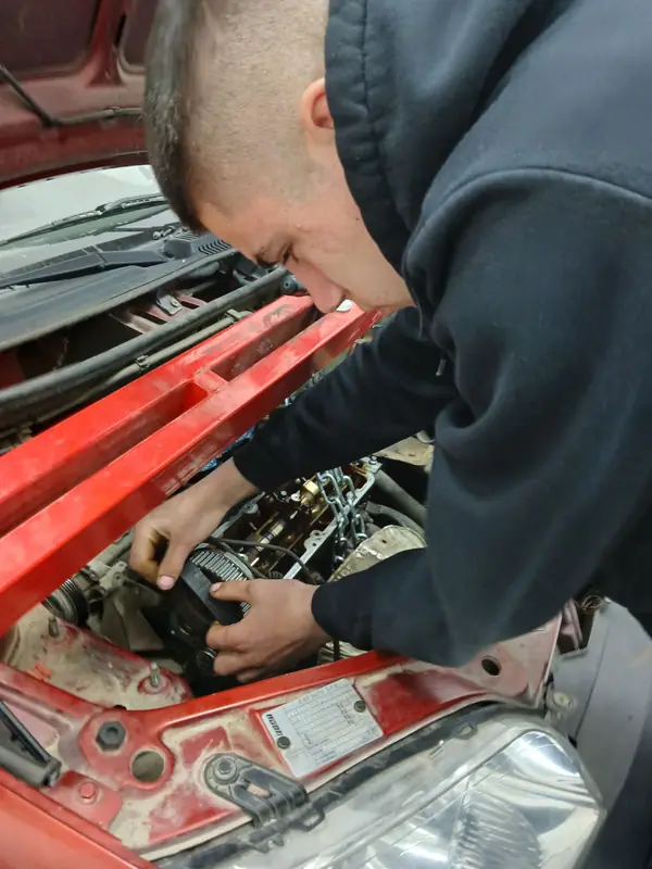 Učenik radi na motoru vozila u školskoj radionici