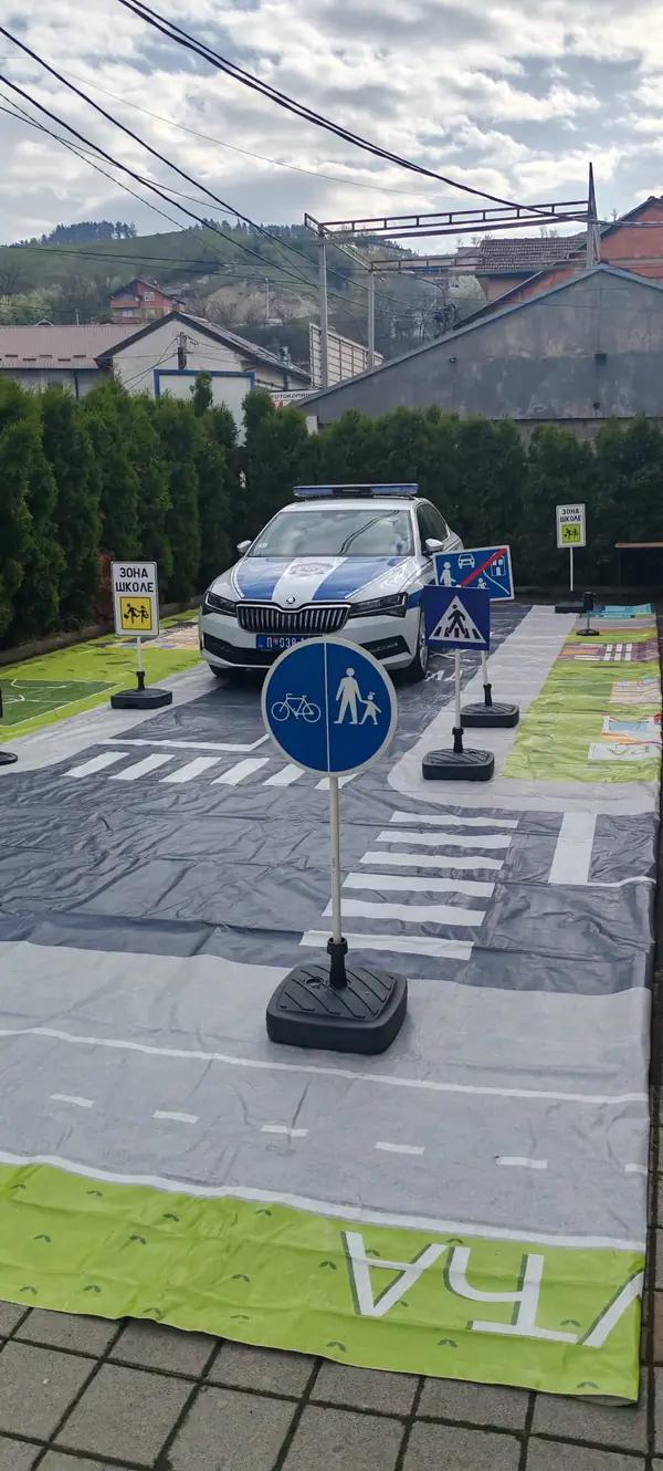 Saobraćajni poligon sa znakovima i policijskim vozilom ispred škole